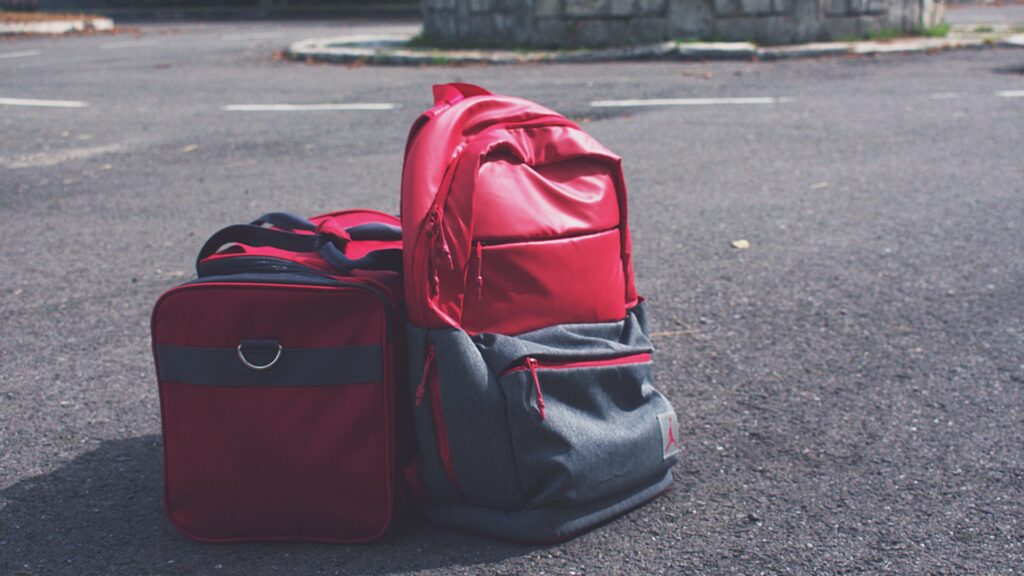 Red backpack and travel bag on the road